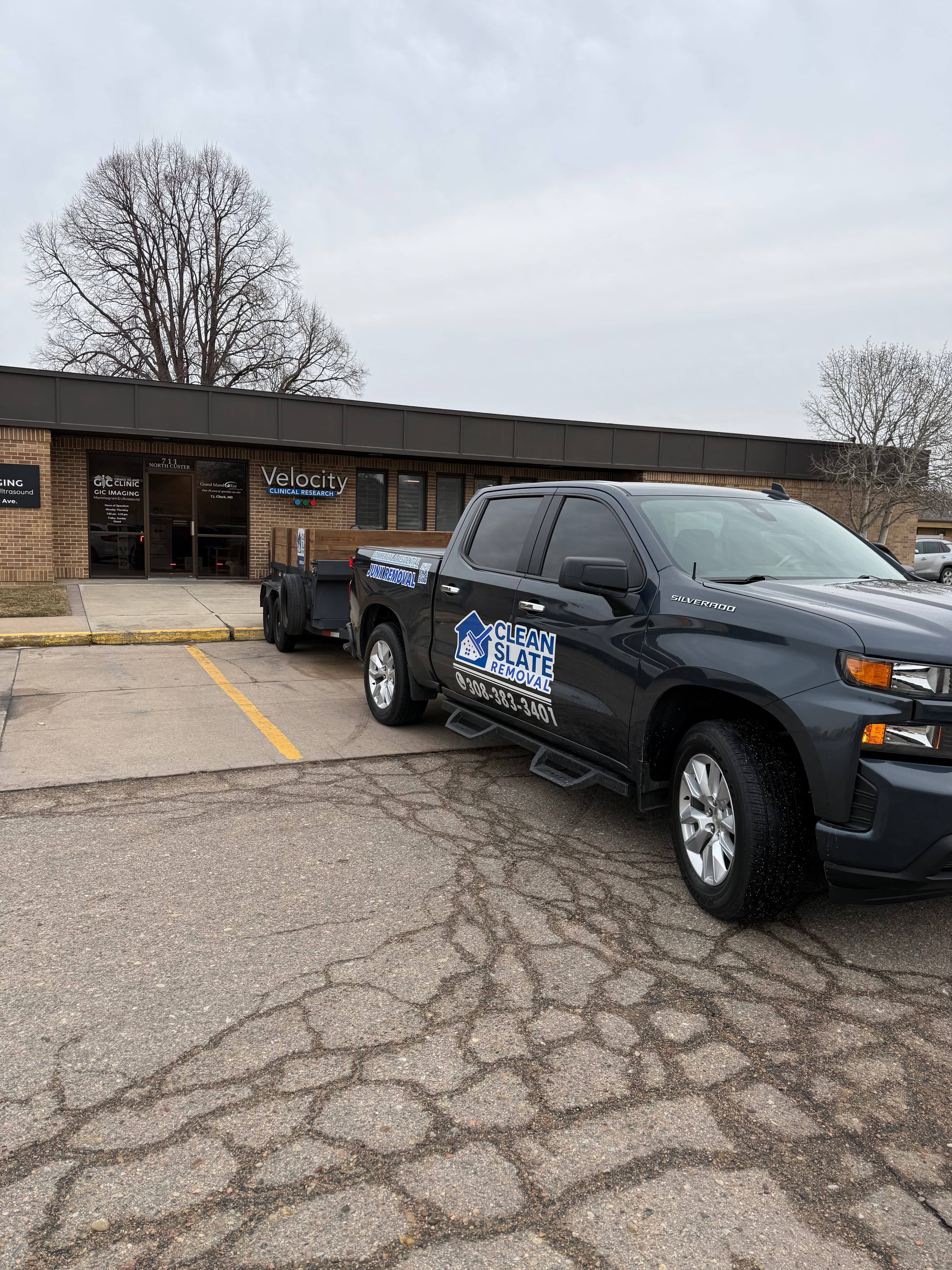 Dark gray Chevrolet Silverado with Clean Slate Removal logo parked outside Velocity Clinical Research building.