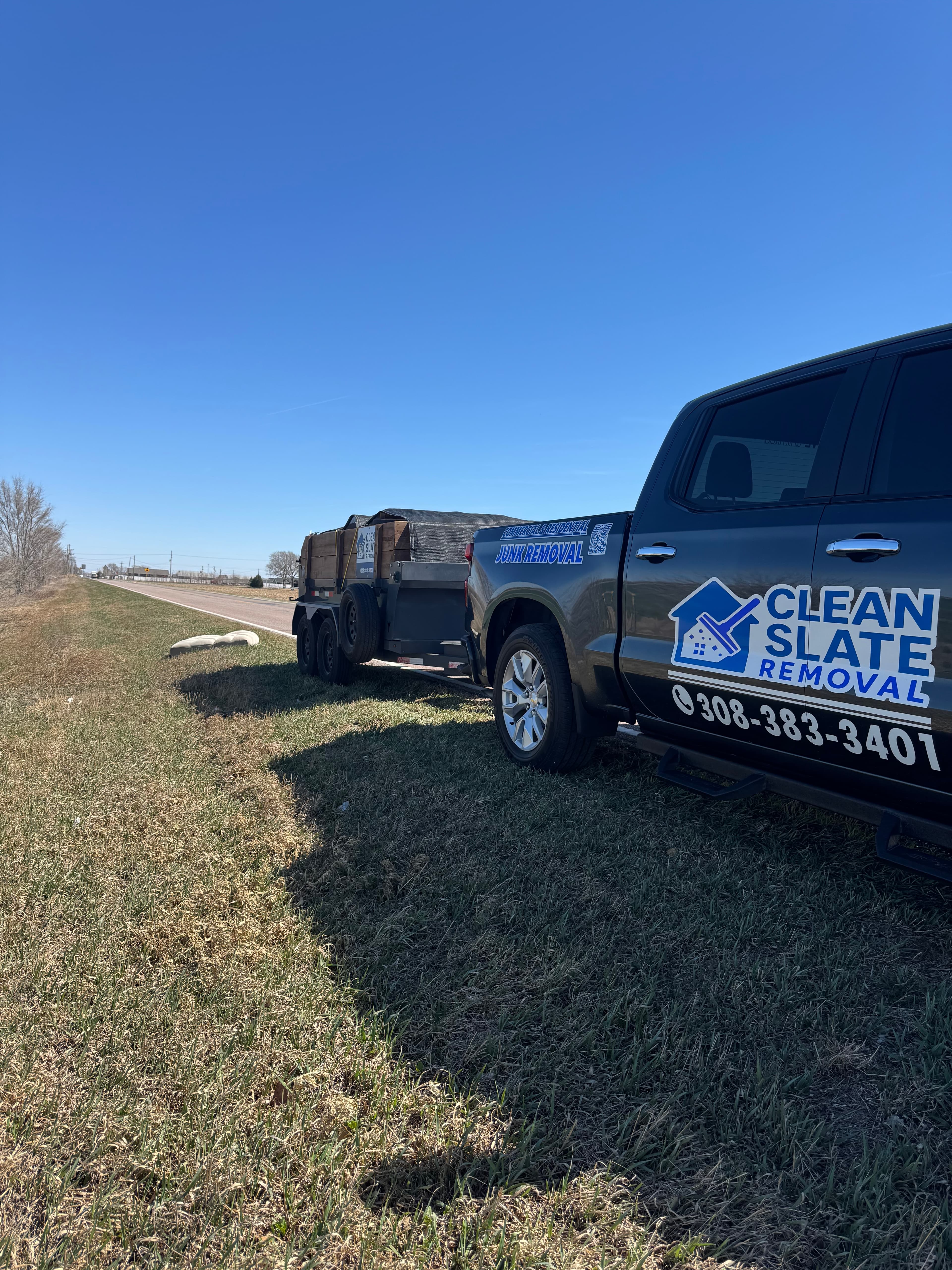 Clean Slate Removal truck and trailer filled with debris parked on a rural roadside.
