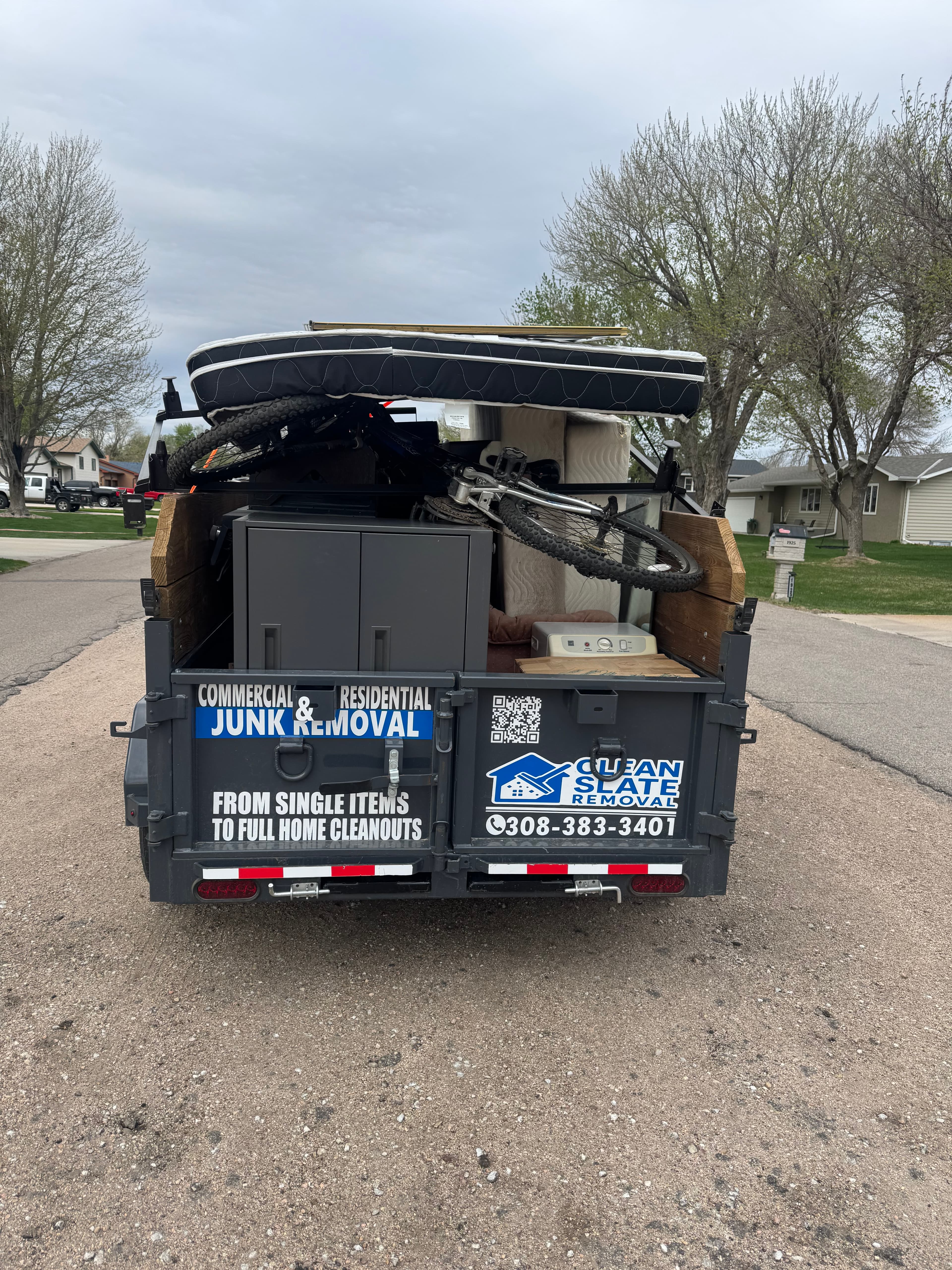 Clean Slate Removal trailer filled with household junk like a mattress and a bicycle.
