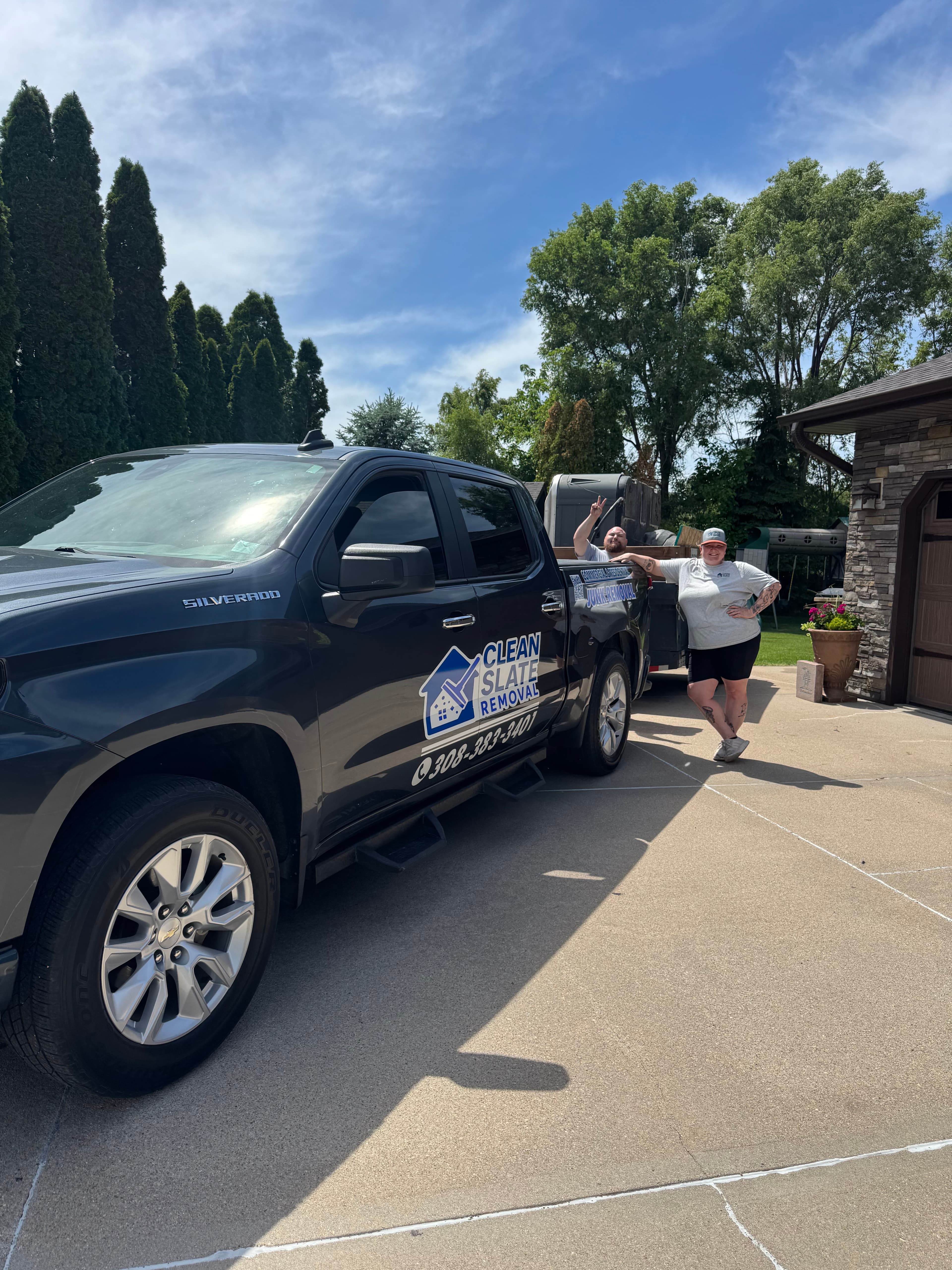 Black Clean Slate Removal pickup truck parked on a driveway with two workers posing.
