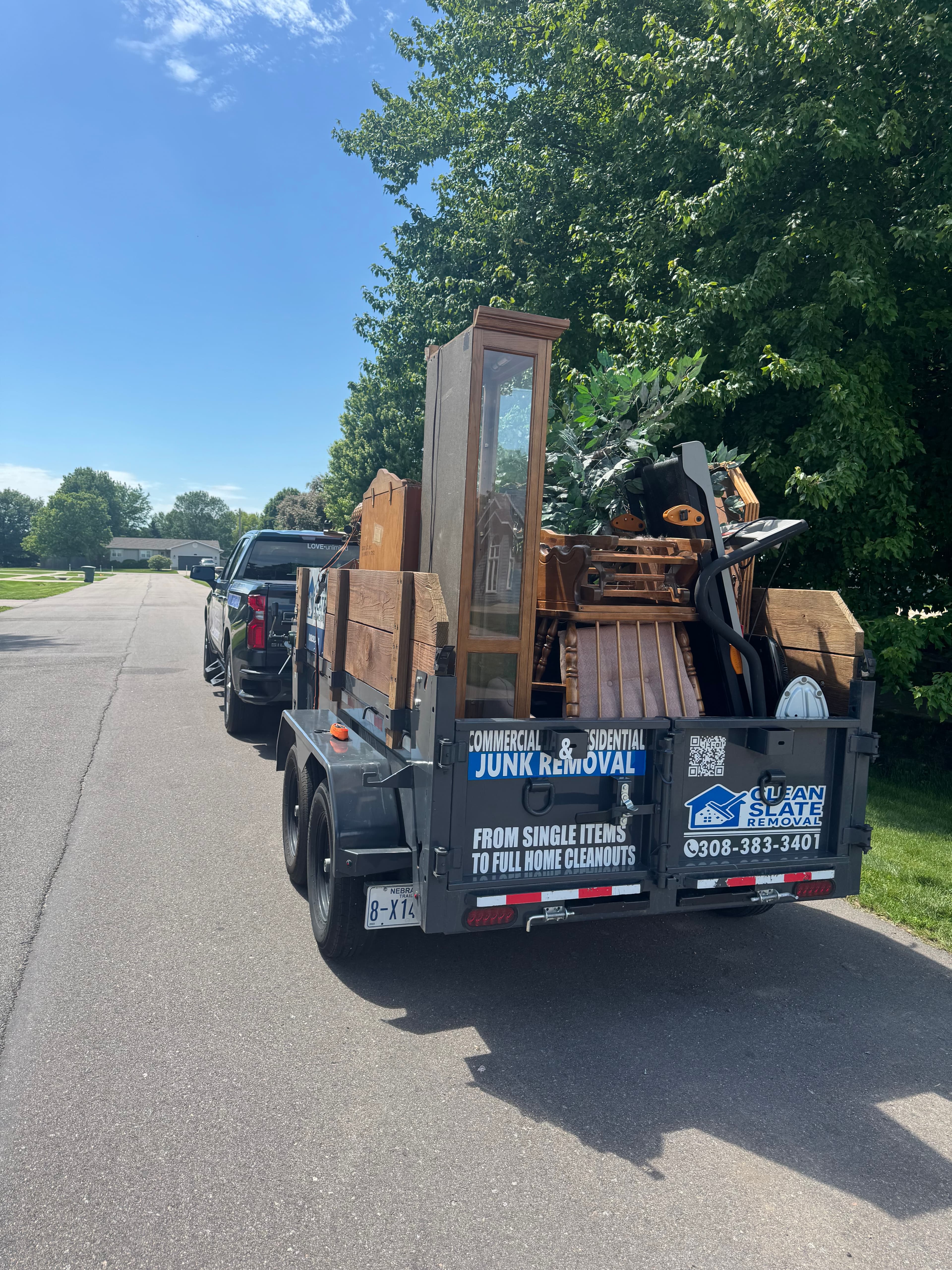 Clean Slate Removal trailer loaded with furniture being towed by a black pickup truck.